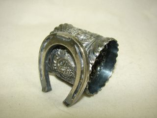 Figural silver plate napkin ring of horseshoe leaning against fancy