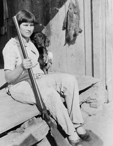 1930 photo Girl, holding double barrel shotgun, seated, with dog. The